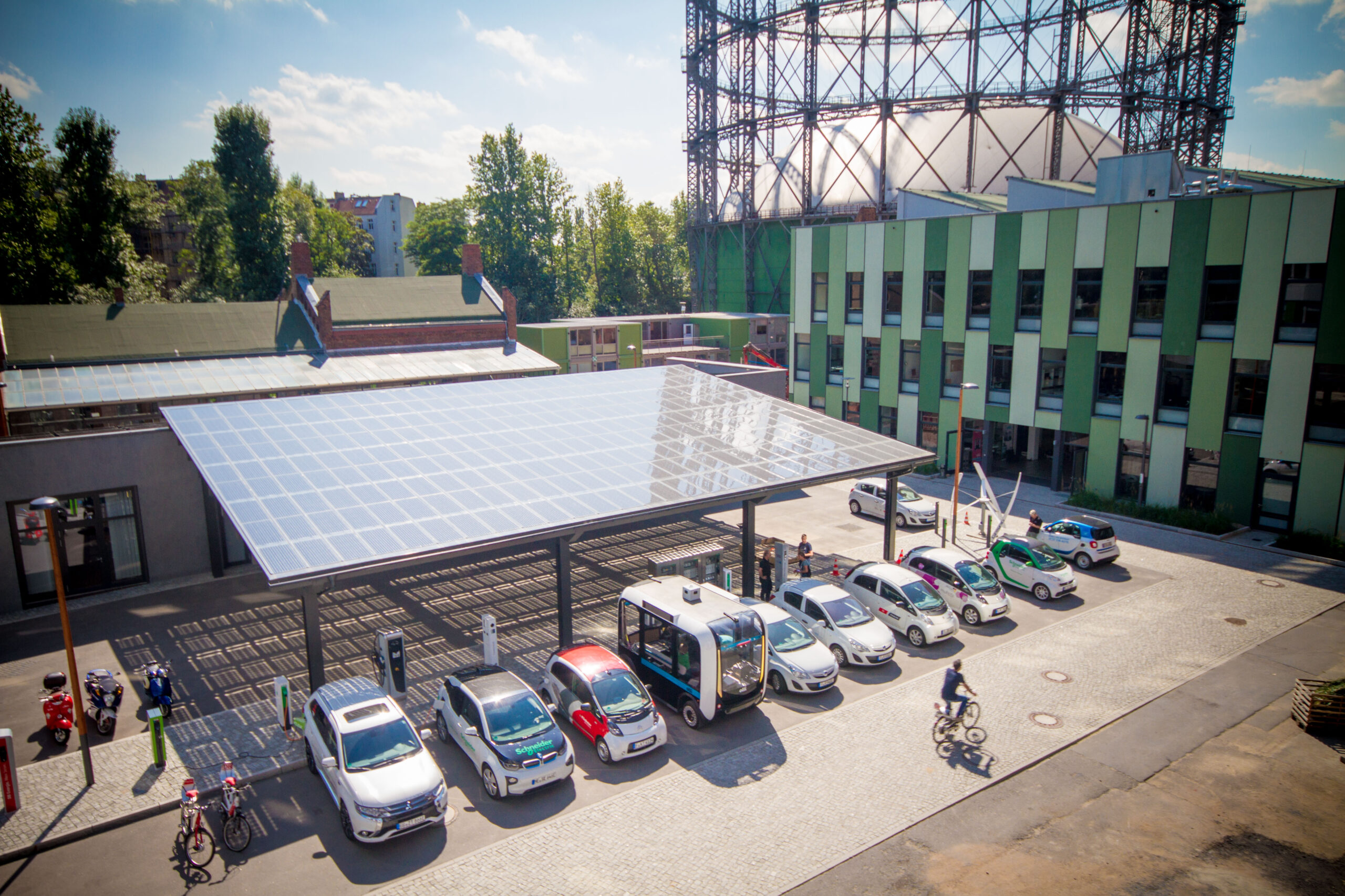 Mobilitässtation am EUREF Campus in Berlin, Autos an E-Ladesäulen und das Gasometer im Hintergrund